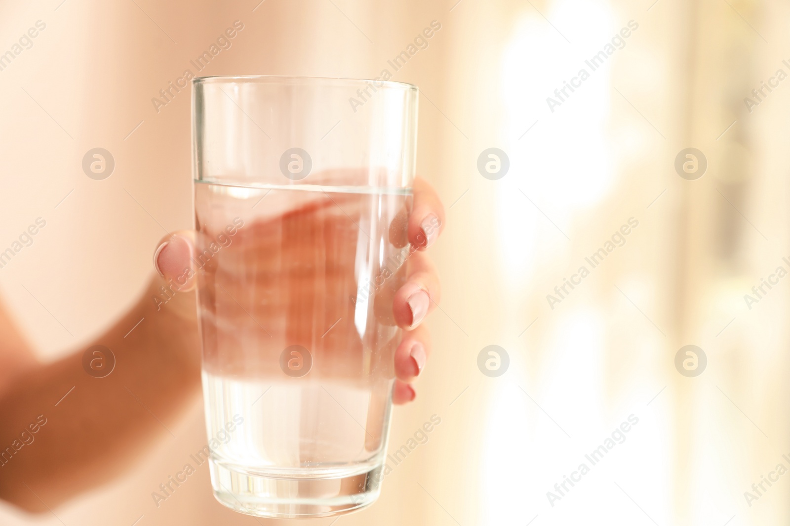 Photo of Woman holding glass with water on light background, closeup. Space for text