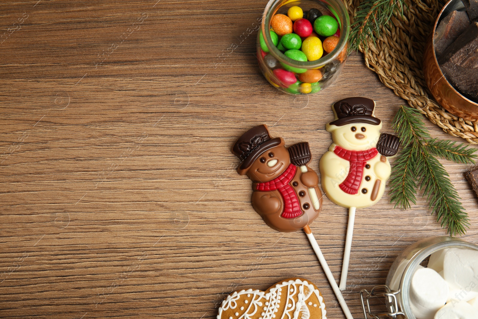 Photo of Flat lay composition with funny chocolate snowmen candies on wooden table. Space for text