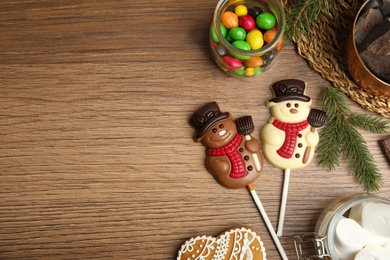 Flat lay composition with funny chocolate snowmen candies on wooden table. Space for text