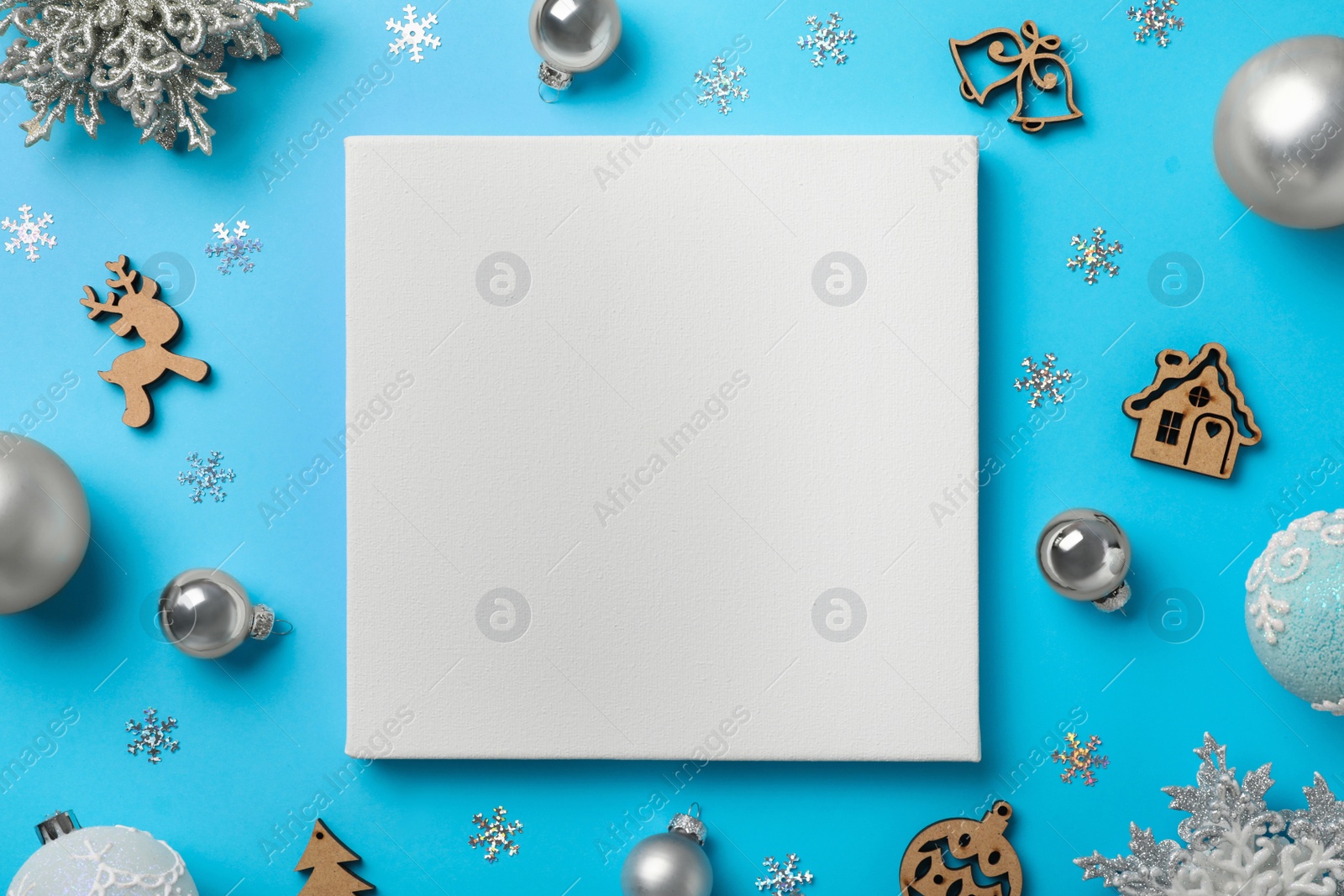 Photo of Flat lay composition with blank canvas and Christmas decor on light blue background. Mockup for design