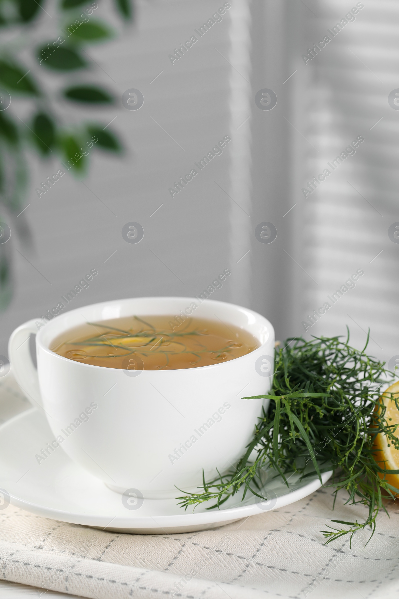 Photo of Aromatic herbal tea and fresh tarragon sprigs on table. Space for text