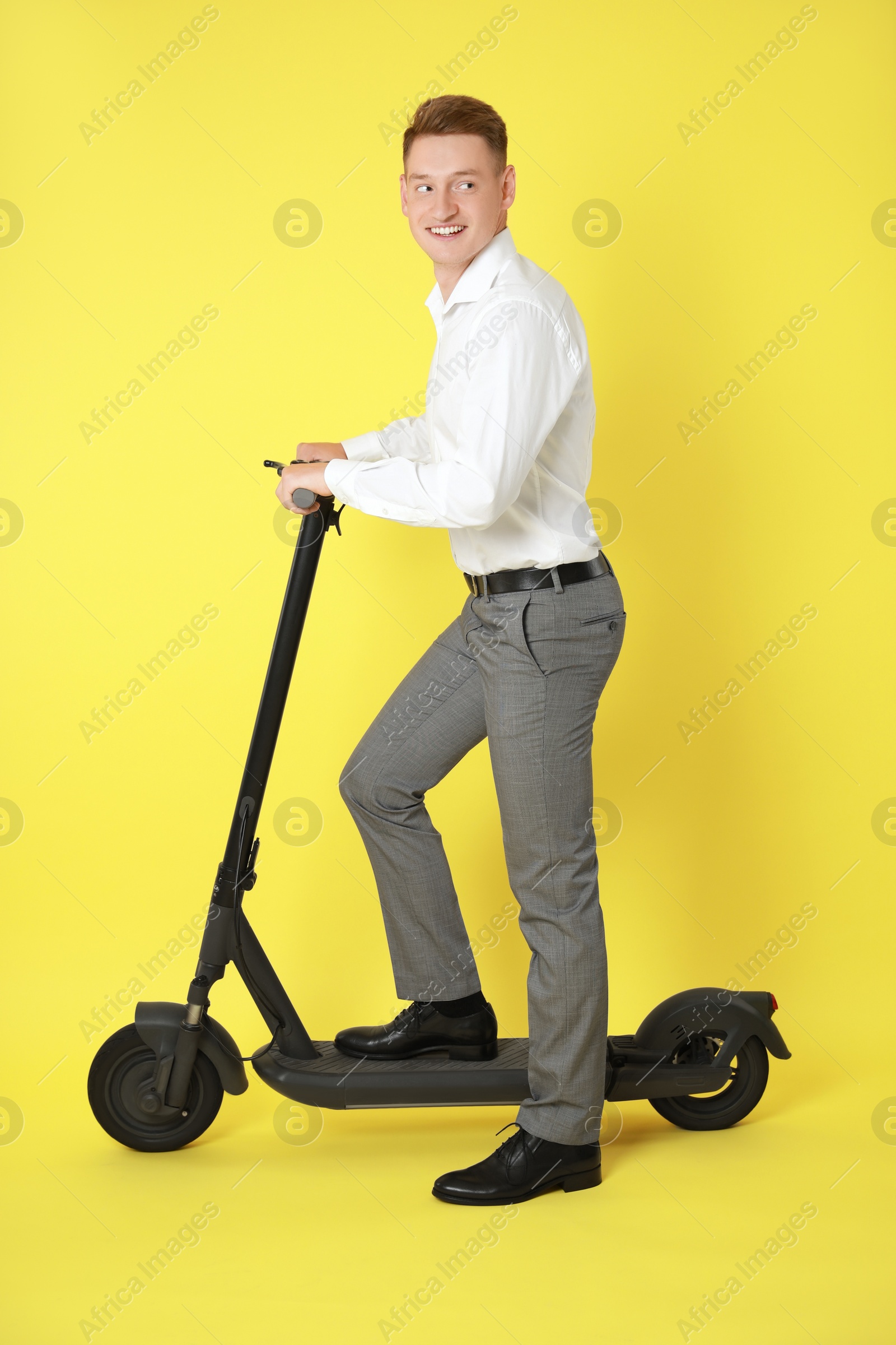 Photo of Happy man with modern electric kick scooter on yellow background