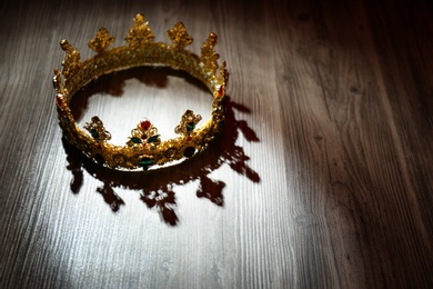 Photo of Beautiful ancient crown on wooden table, space for text. Fantasy item