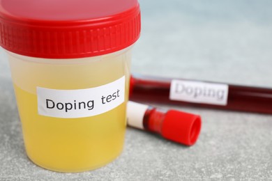 Photo of Jar of urine with words Doping test on light grey stone table, closeup. Space for text