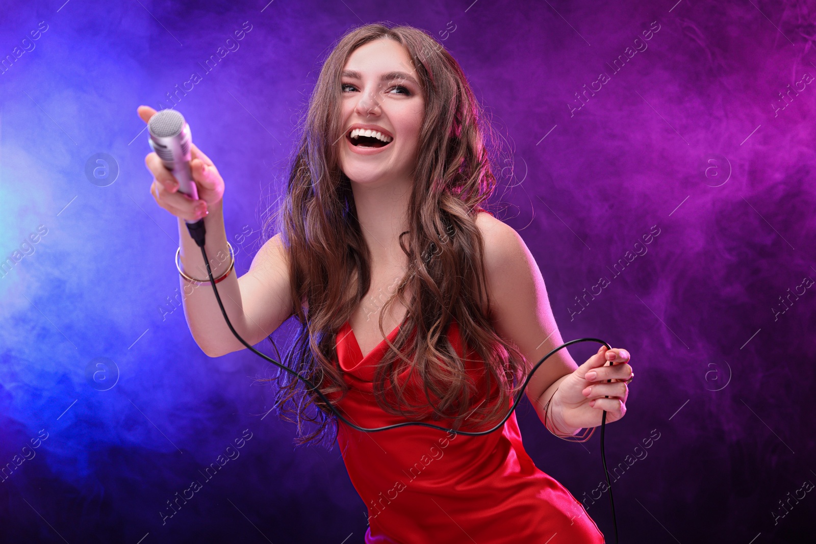 Photo of Emotional singer giving microphone to others in color lights