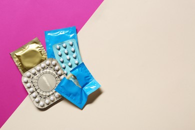 Photo of Contraceptive pills and condoms on color background, flat lay with space for text. Different birth control methods
