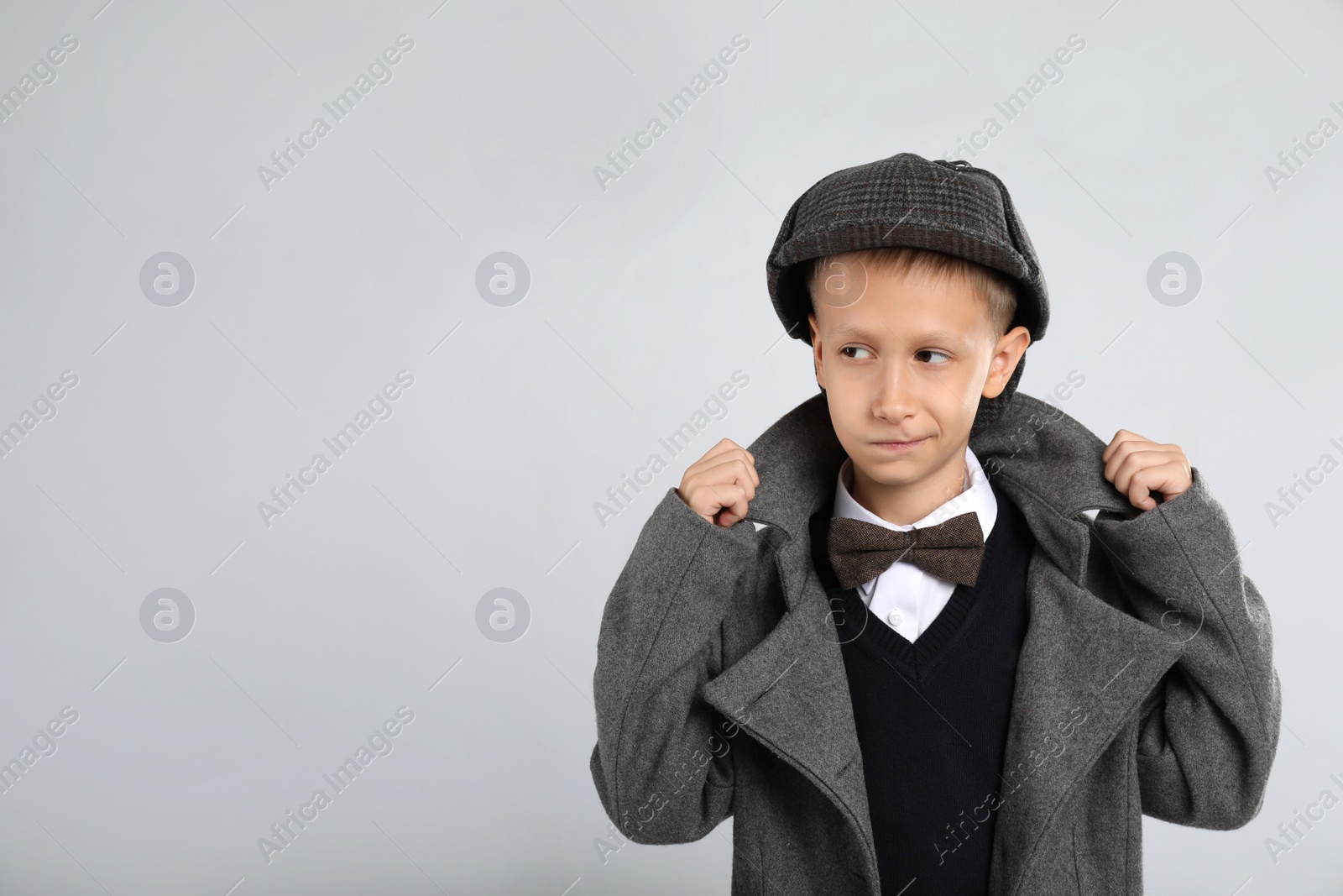 Photo of Cute little detective in hat and coat on grey background. Space for text