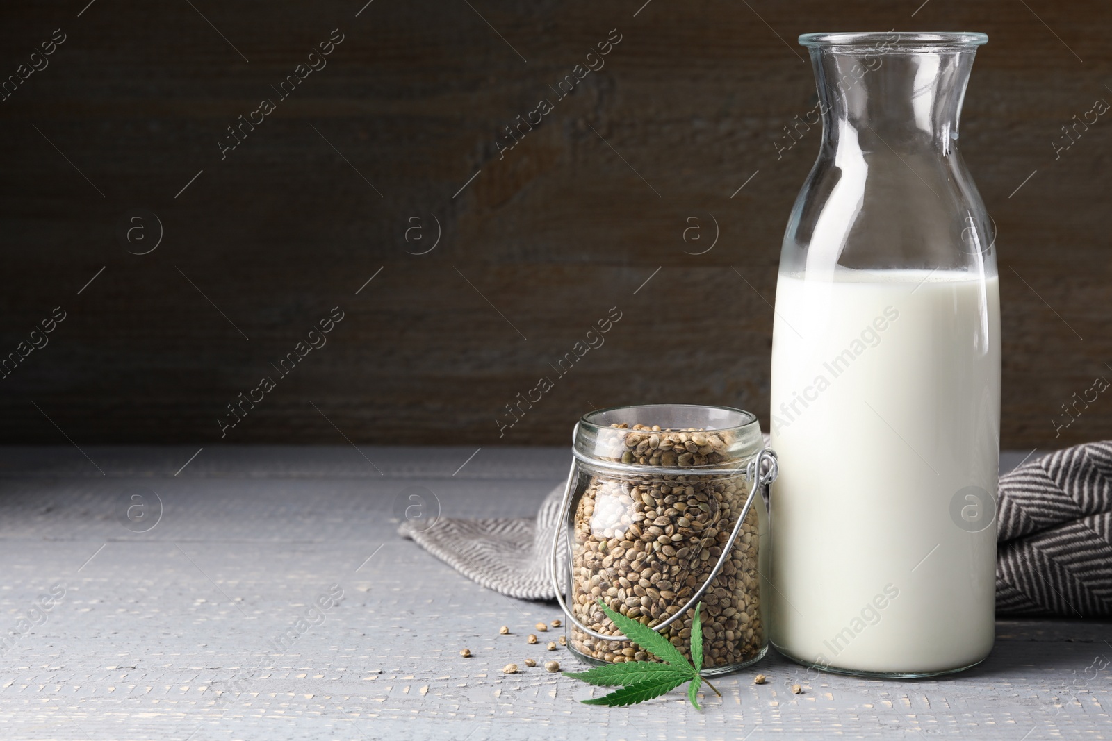 Photo of Composition with bottle of hemp milk on grey wooden table. Space for text