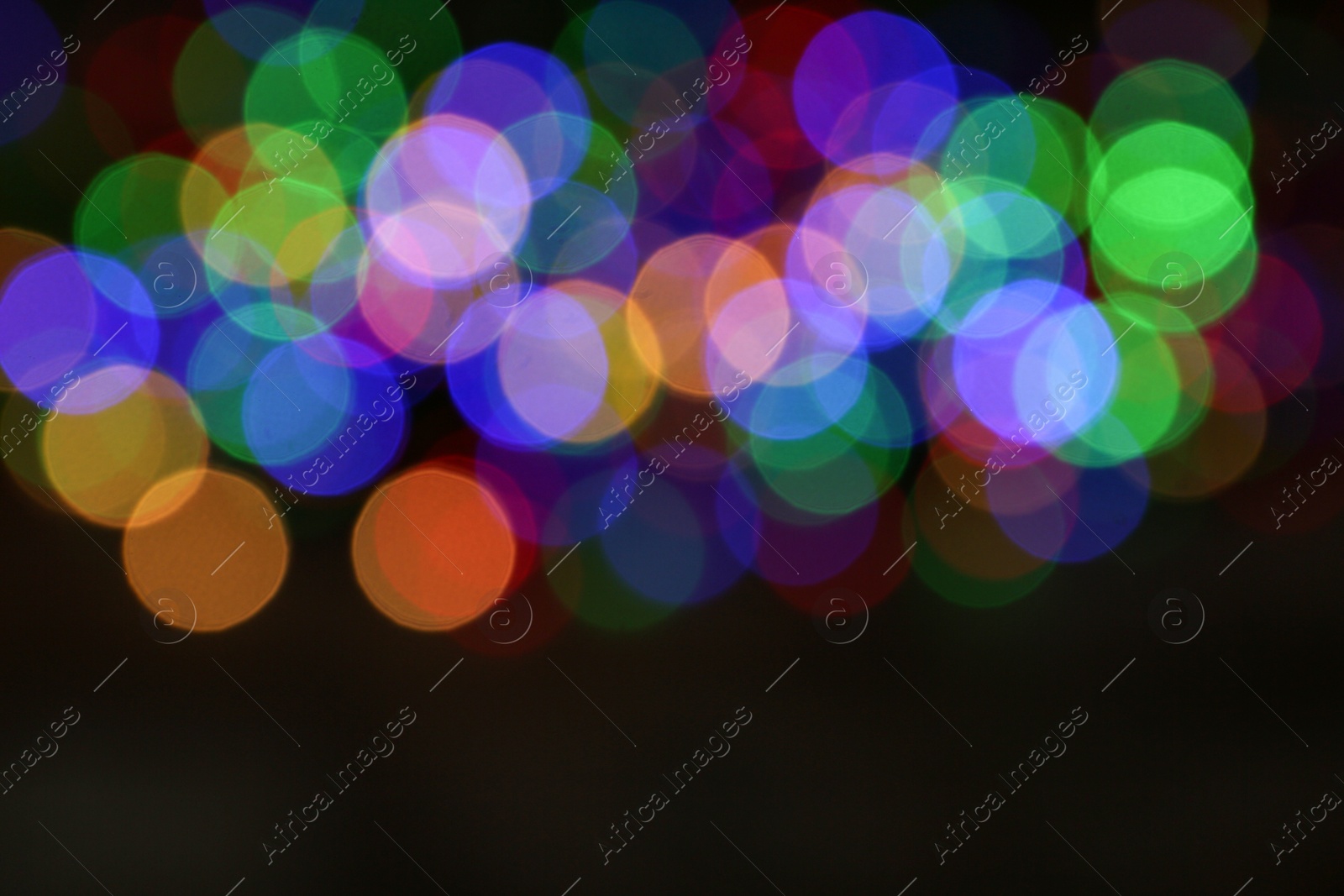 Photo of Blurred view of colorful Christmas lights on dark background