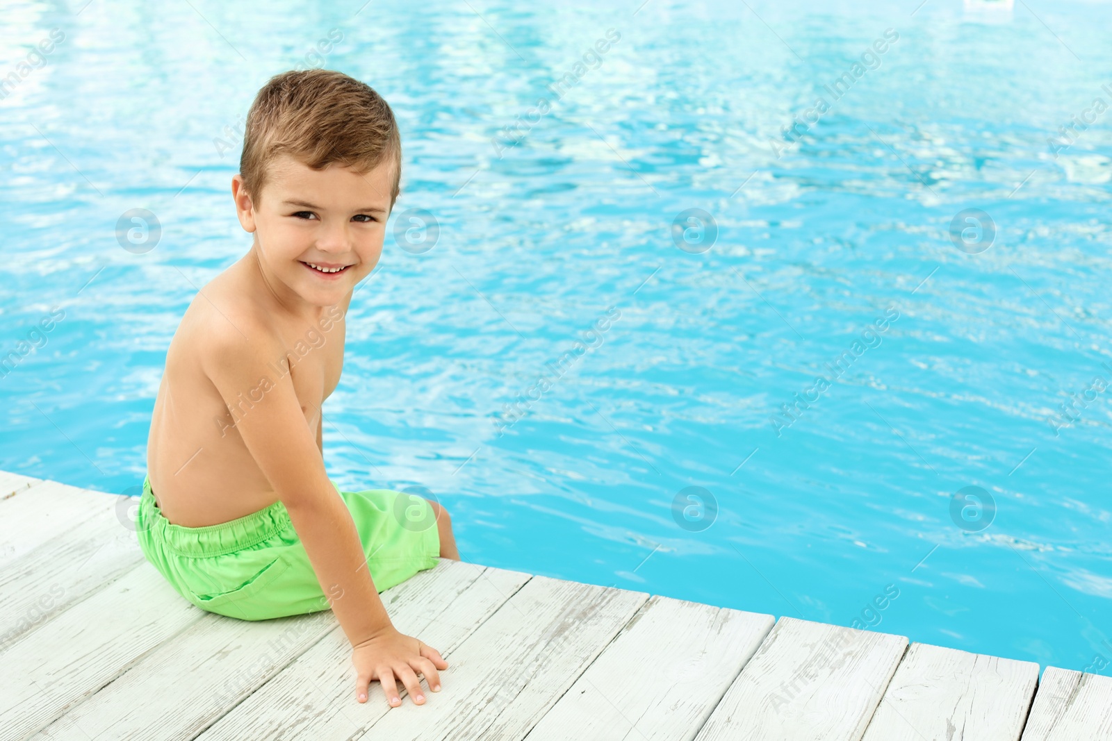 Photo of Little child near outdoor swimming pool. Dangerous situation