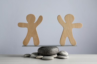 Photo of Balancing wooden human figures on stones against light grey background