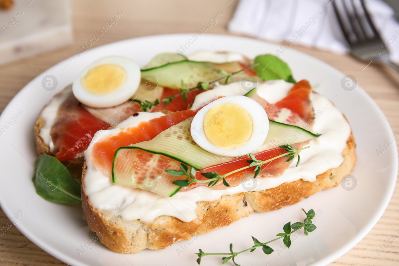 Photo of Plate of delicious bruschettas with salmon on wooden table, closeup