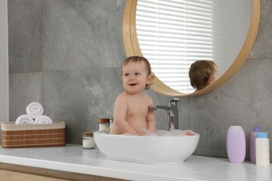 Photo of Cute little baby bathing in sink at home