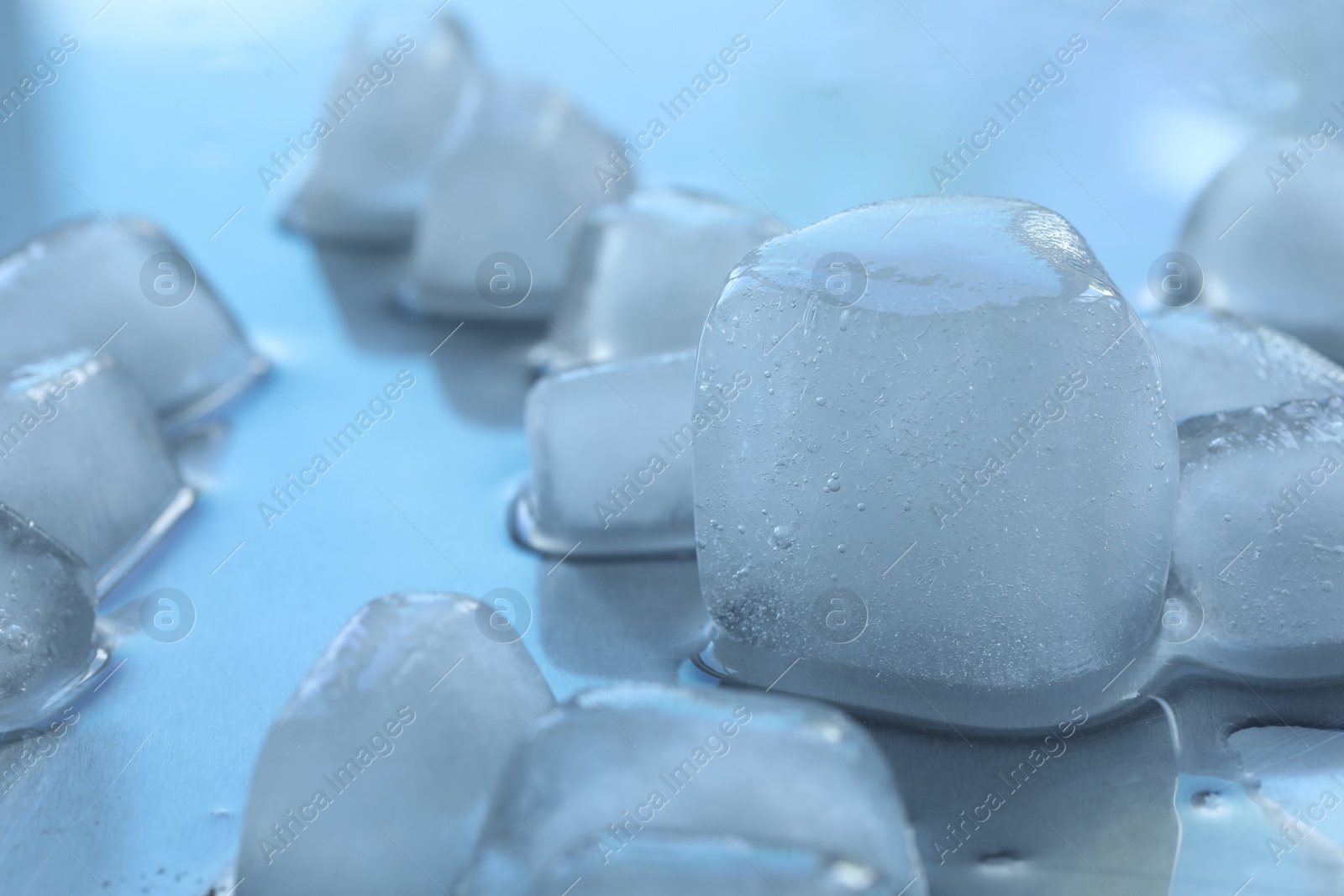 Photo of Many crystal clear ice cubes on light surface, selective focus. Space for text