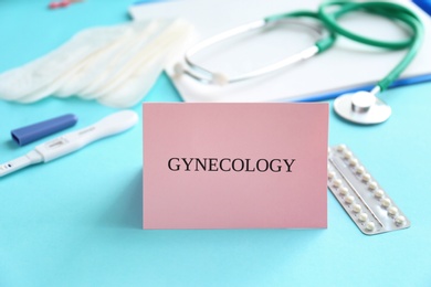 Card with word GYNECOLOGY and birth control pills on table