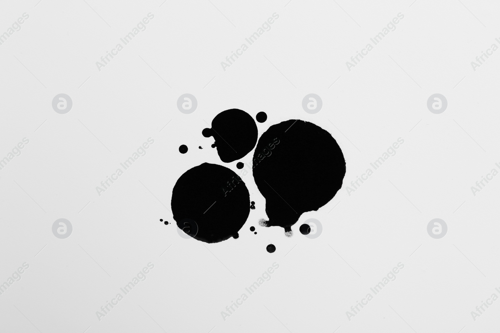 Photo of Blots of black ink on white background, top view