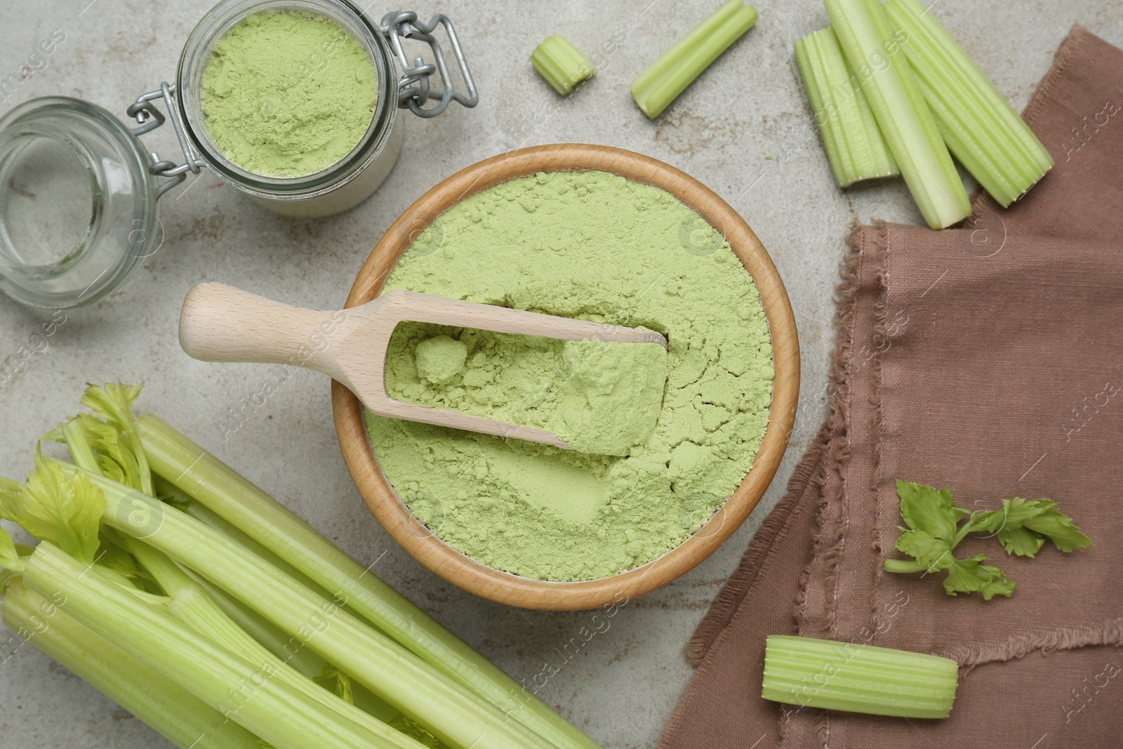 Photo of Natural celery powder and fresh stalks on grey table, flat lay