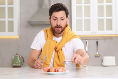 Man with sausages at table in kitchen