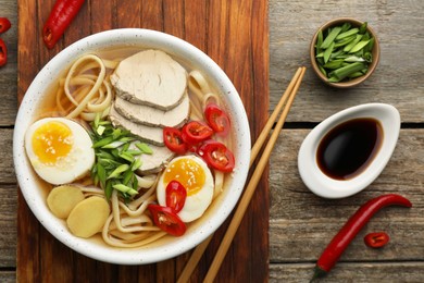 Photo of Delicious ramen in bowl served on wooden table, flat lay. Noodle soup