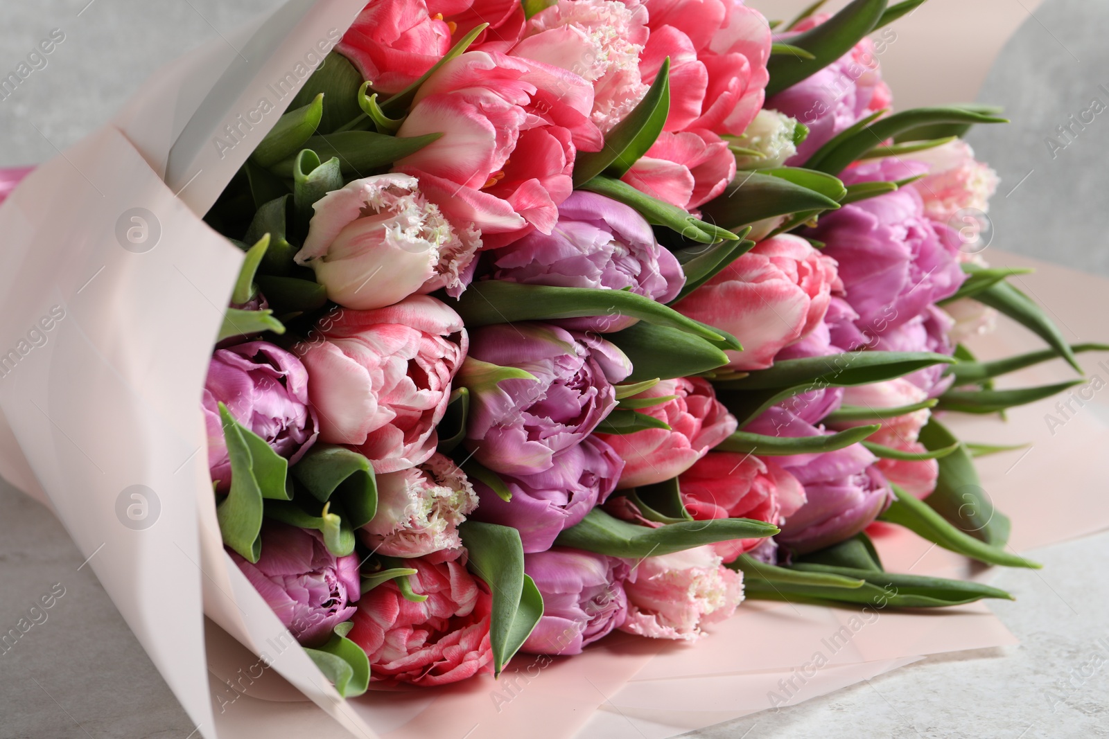 Photo of Bouquet of beautiful tulips on white table, closeup