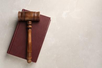 Photo of Wooden gavel and book on light textured table, top view. Space for text