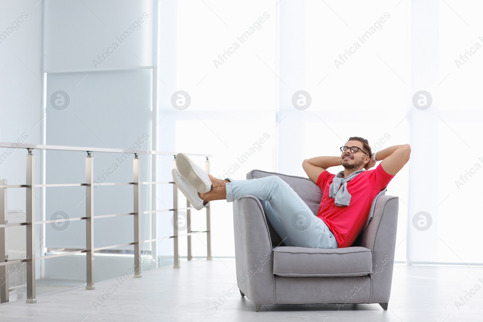 Photo of Handsome young man resting in armchair indoors. Space for text