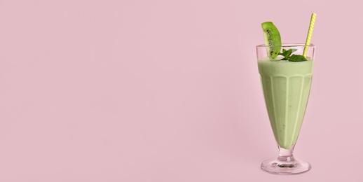 Photo of Tasty fresh milk shake with kiwi on pink background. Space for text