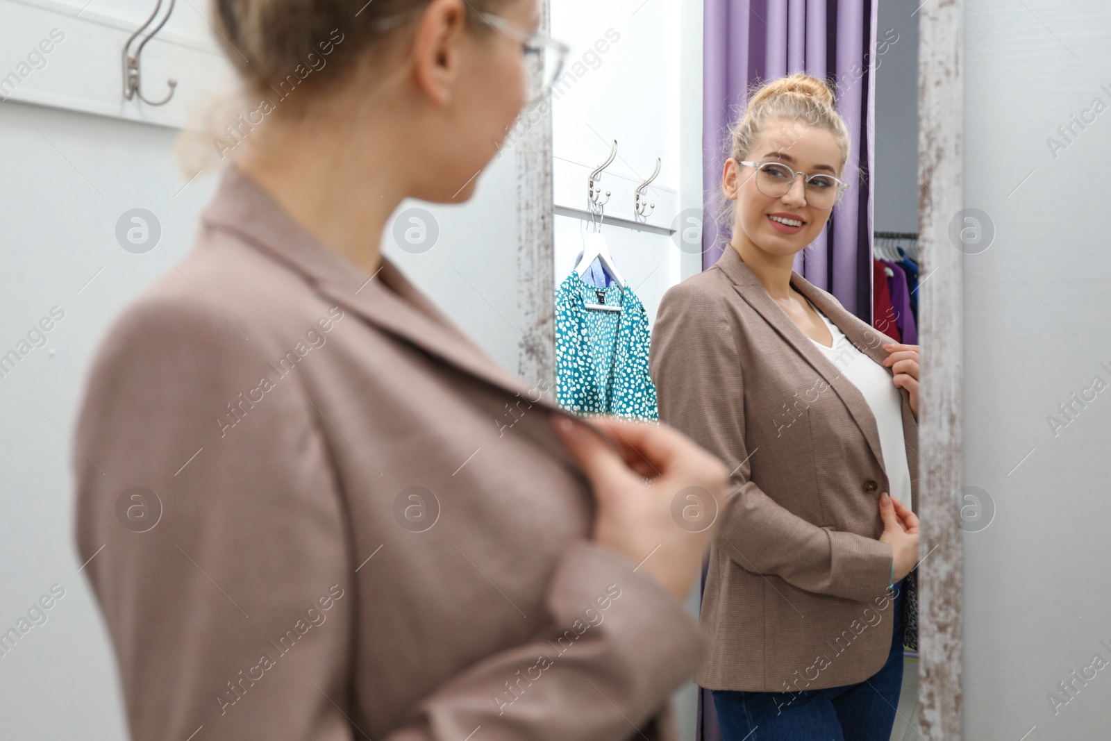 Photo of Young woman trying on clothes in dressing room. Fashion store