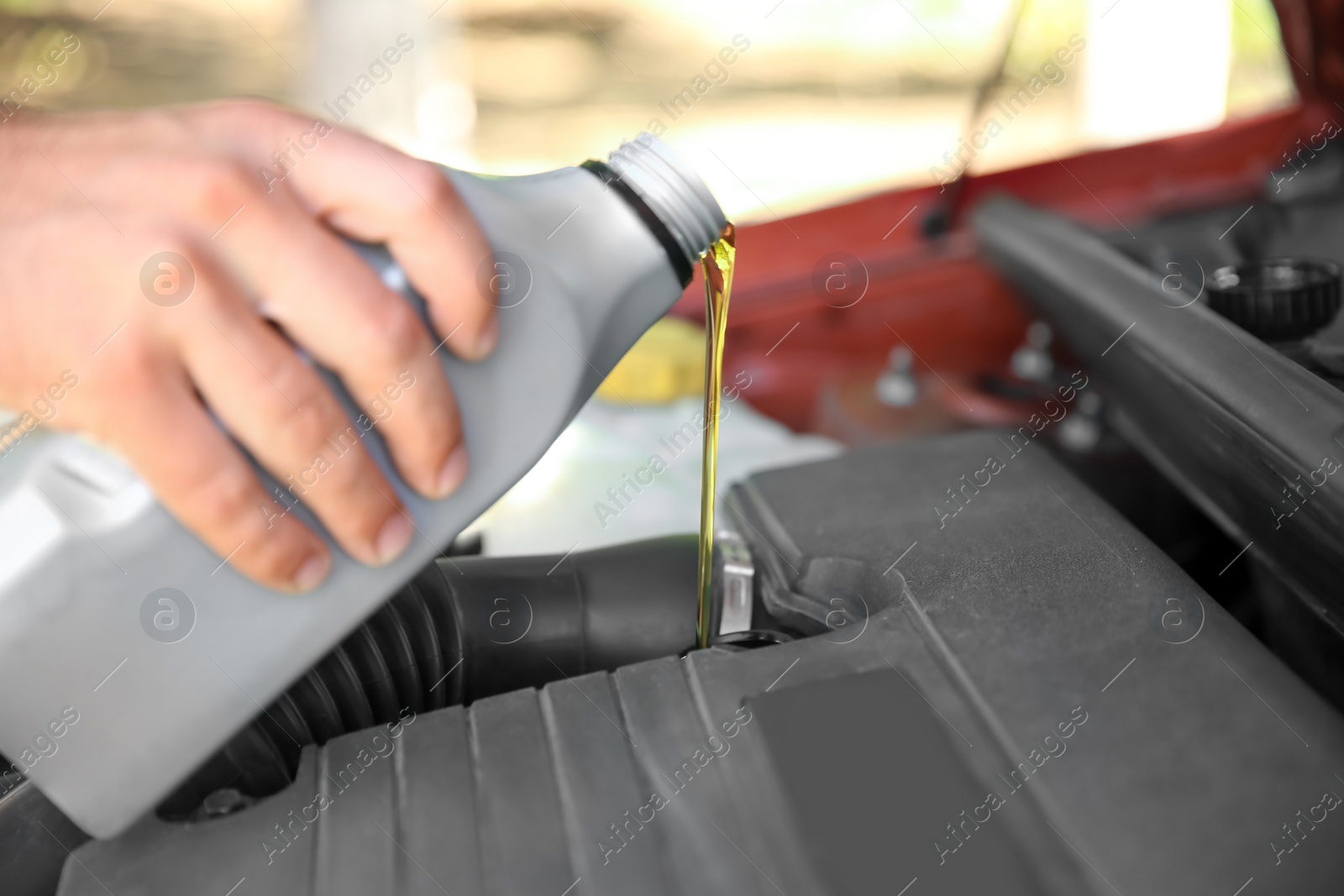 Photo of Mechanic pouring oil into car engine, closeup