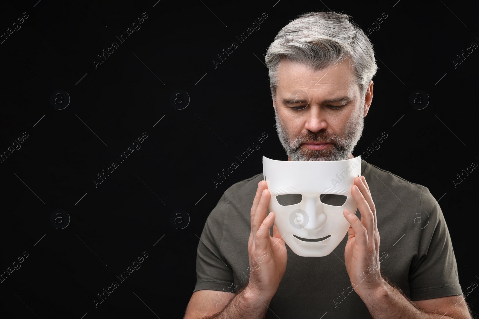 Photo of Multiple personality concept. Man with mask on black background. Space for text