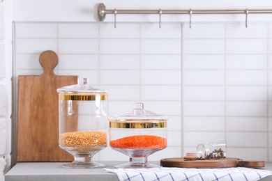 Jars with cereals on light grey table in modern kitchen