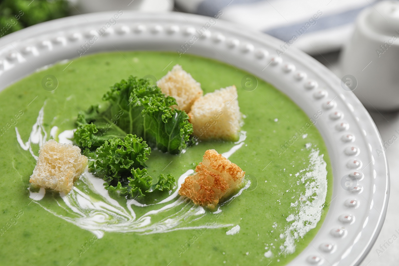 Photo of Tasty kale soup with croutons on table, closeup