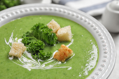 Tasty kale soup with croutons on table, closeup