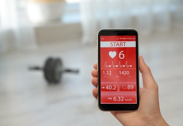 Photo of Young woman using fitness app on smartphone indoors, closeup. Space for text