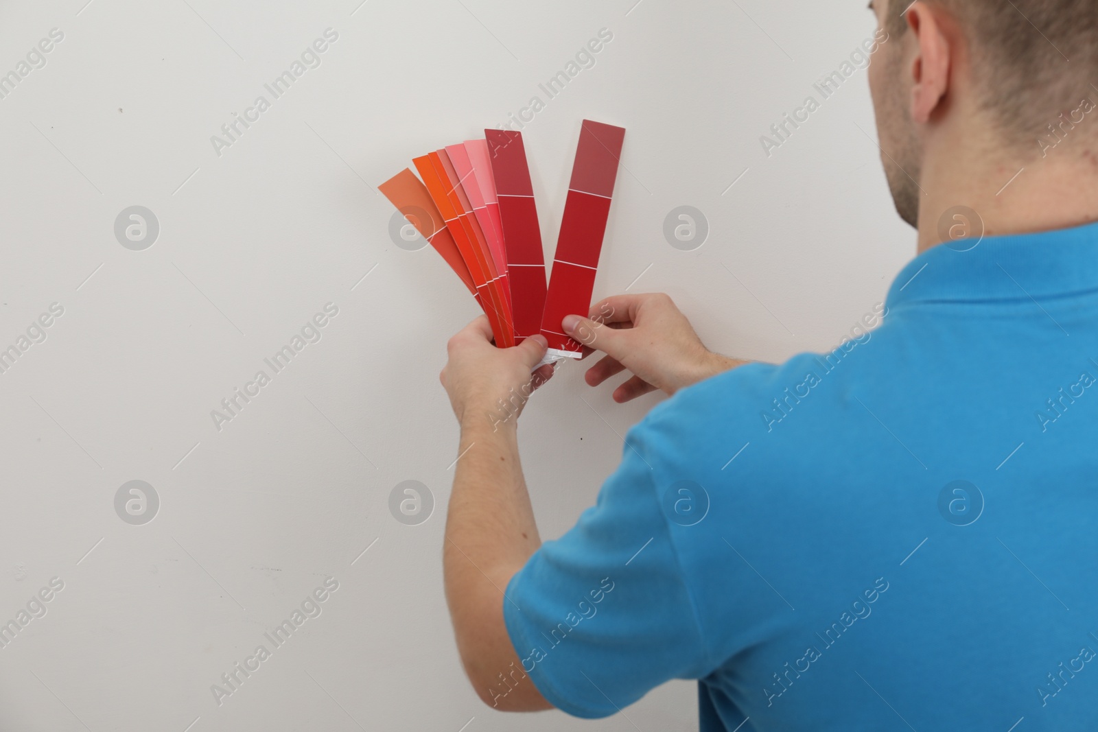 Photo of Man with palette choosing color for painting wall indoors, closeup. Interior design