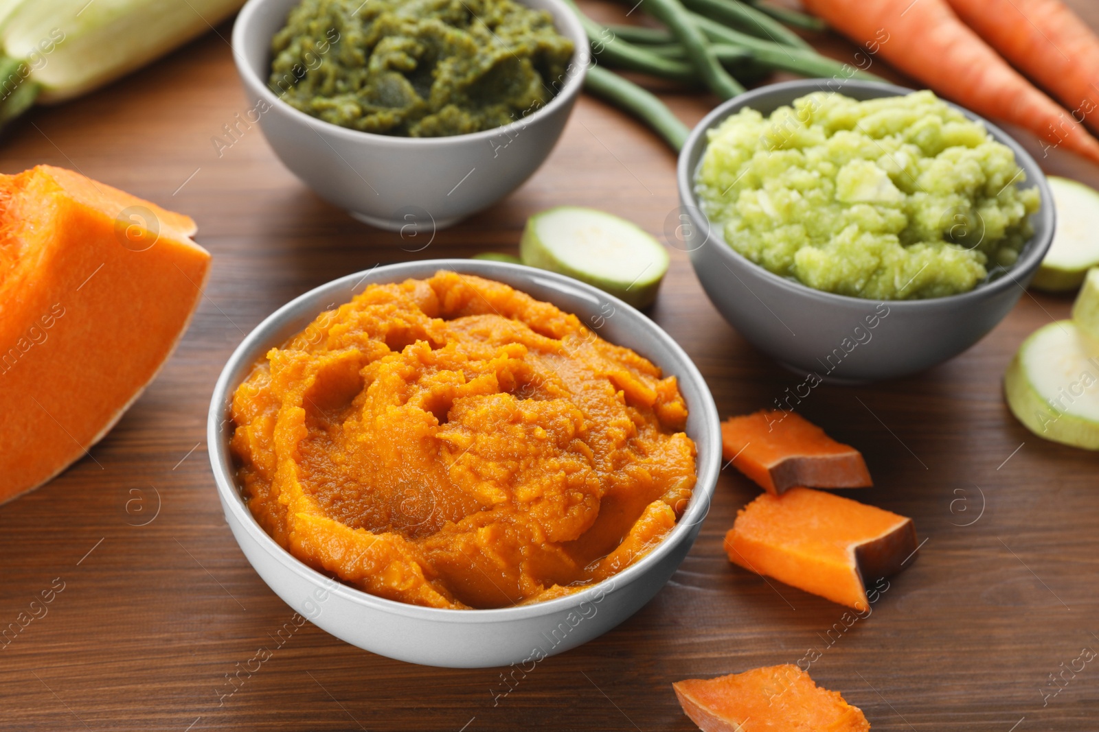 Photo of Tasty puree in bowls and ingredients on wooden table