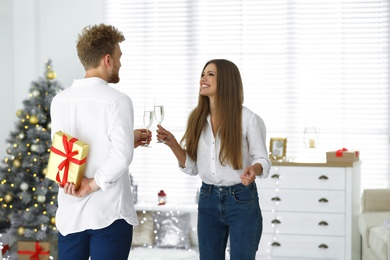 Photo of Young man giving Christmas gift to his girlfriend at home