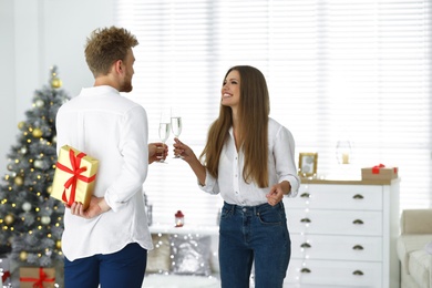 Young man giving Christmas gift to his girlfriend at home