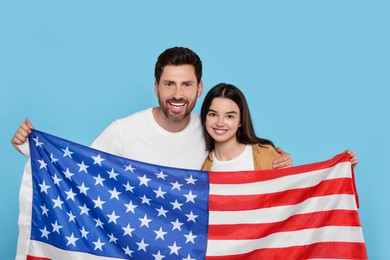 Photo of 4th of July - Independence Day of USA. Happy man and his daughter with American flag on light blue background