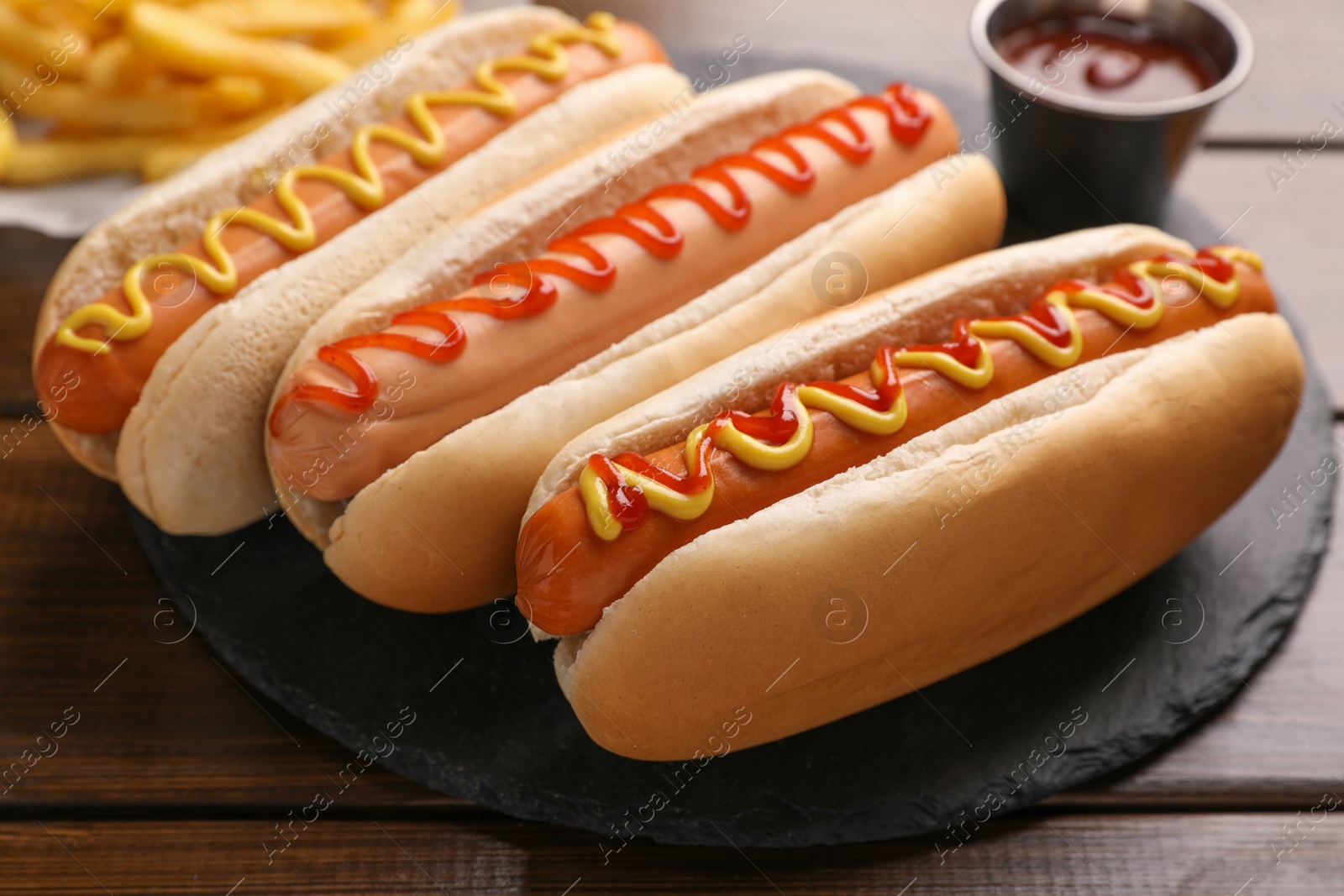 Photo of Delicious hot dogs with sauces on wooden table, closeup