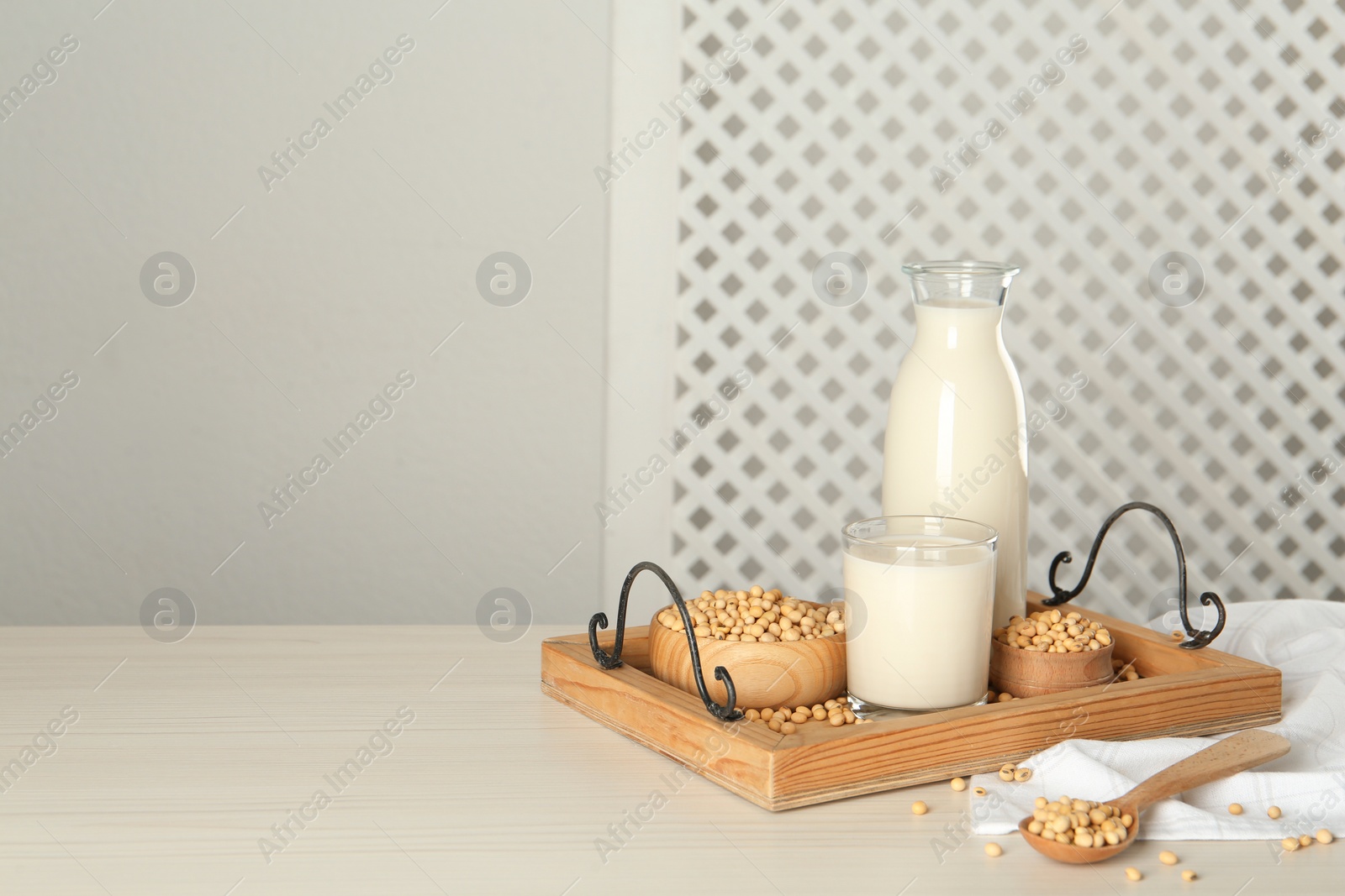 Photo of Soy milk and beans on wooden table, space for text