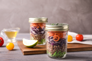 Glass jars with healthy meal on light grey wooden table