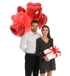 Photo of Happy young couple with heart shaped balloons and gift box isolated on white. Valentine's day celebration