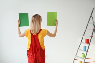 Young woman choosing color for wall on white background