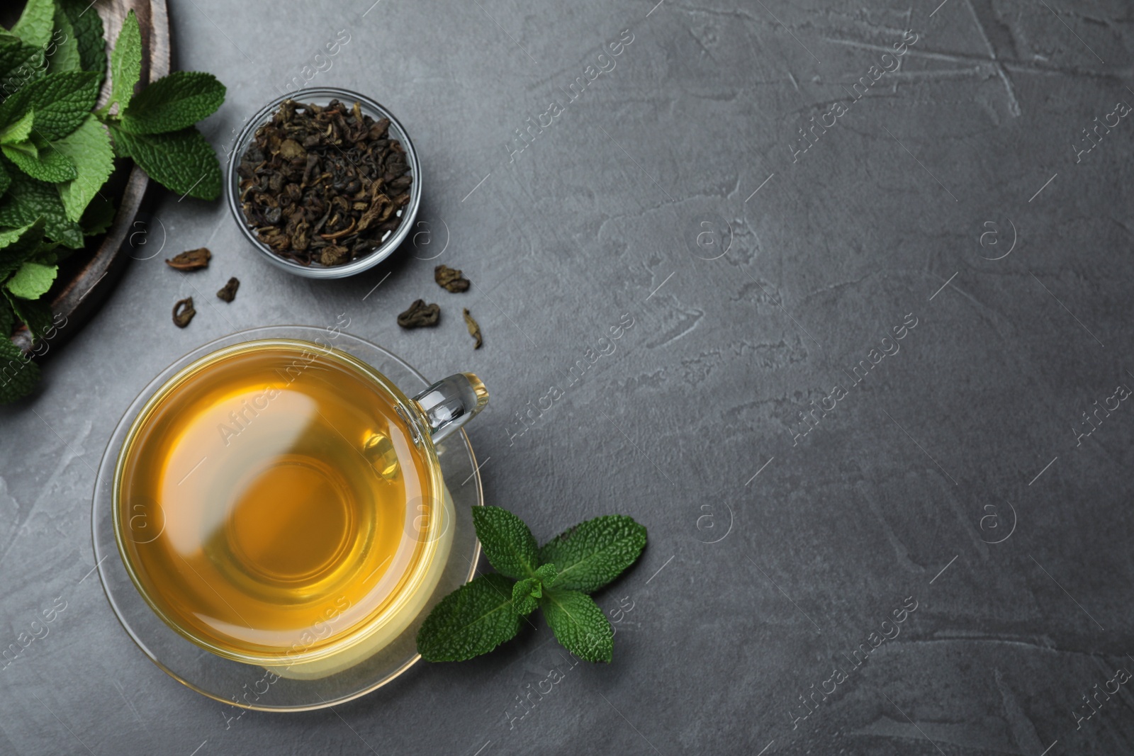 Photo of Cup of hot aromatic mint tea on grey table, flat lay. Space for text