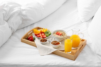 Photo of Wooden tray with tasty breakfast on bed