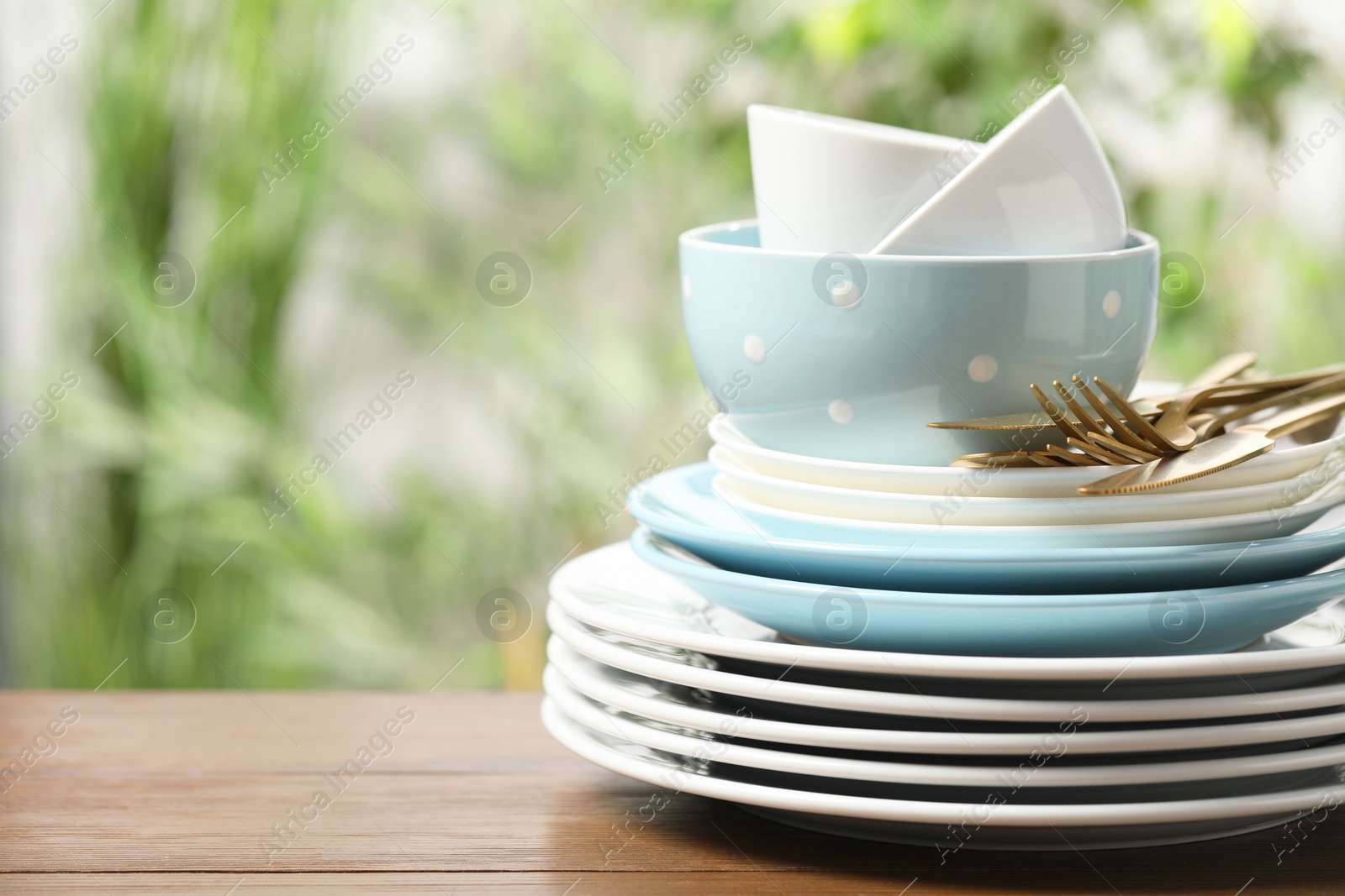 Photo of Beautiful ceramic dishware and cutlery on wooden table outdoors, space for text
