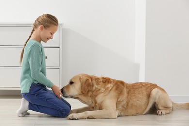 Cute child with her Labrador Retriever on floor at home. Adorable pet