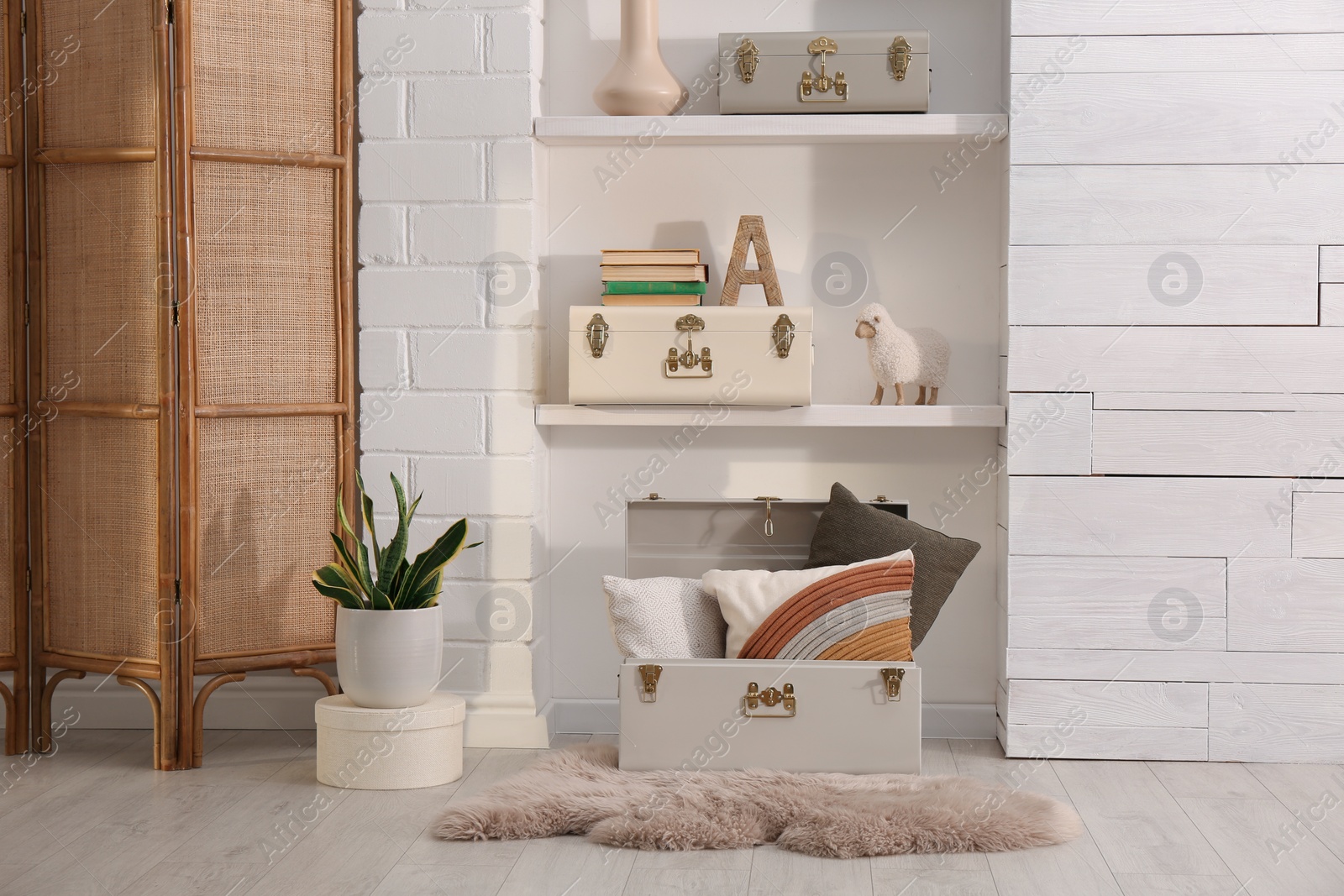 Photo of Stylish storage trunks, plant and different decor elements near white wall indoors. Interior design