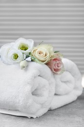 Photo of Rolled towels and flowers on grey table indoors